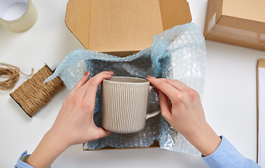 Image showing hands packing mug to parcel box at post office