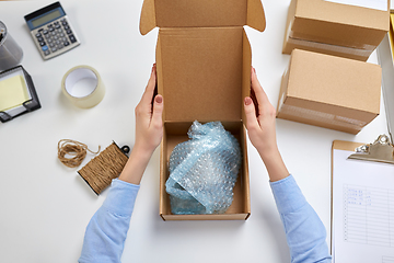 Image showing hands packing mug to parcel box at post office