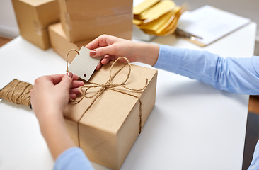 Image showing hands tying name tag to parcel box at post office