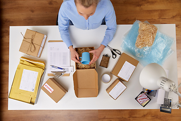 Image showing woman packing mug to parcel box at post office