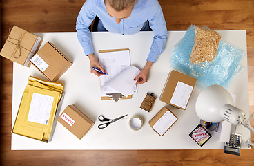 Image showing woman with clipboard and parcels at post office