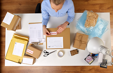 Image showing woman sticking fragile mark to parcel box