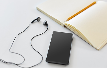 Image showing earphones, smartphone and notebook with pencil