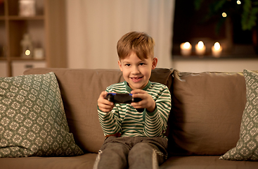 Image showing little boy with gamepad playing video game at home