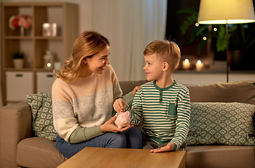 Image showing mother and little son with piggy bank at home