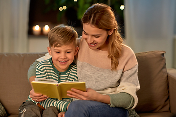 Image showing happy mother and son reading book sofa at home