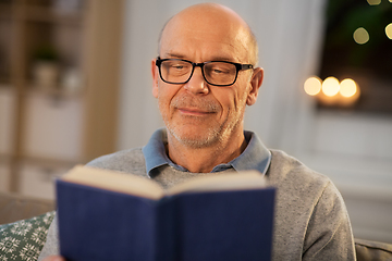 Image showing happy bald senior man on sofa reading book at home