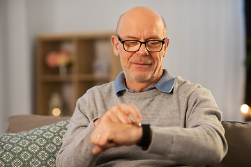 Image showing senior man looking at wristwatch at home