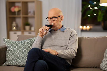 Image showing senior man drinking red wine from glass at home