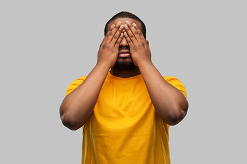 Image showing african american man closing his eyes by hands