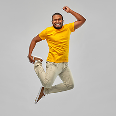 Image showing smiling young african american man jumping in air