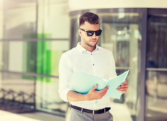 Image showing young man with business file on city street