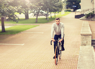 Image showing young man riding bicycle on city street