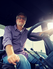 Image showing senior man driving tractor at farm