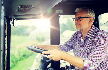 Image showing senior man driving tractor at farm