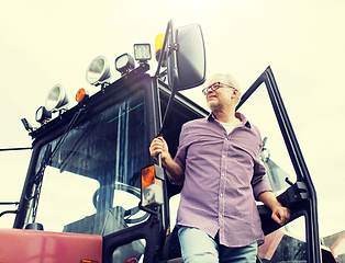 Image showing old man or farmer getting out of tractor at farm