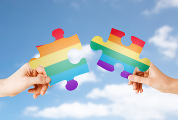 Image showing hands matching puzzle pieces with gay flag colors