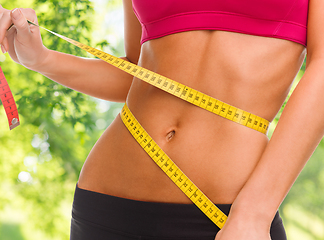 Image showing close up of woman measuring her waist with tape