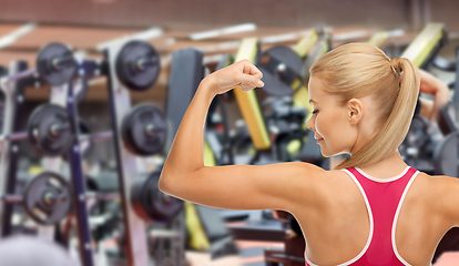 Image showing young sporty woman showing her biceps in gym