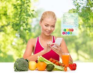 Image showing woman with vegetables pointing at smartphone