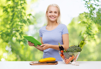 Image showing smiling young woman with tablet pc cooking