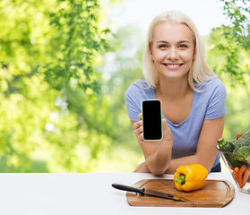 Image showing smiling woman with smartphone cooking vegetables