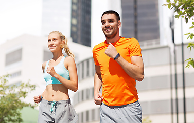 Image showing happy couple with fitness trackers running at city