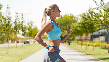 Image showing smiling young woman running outdoors