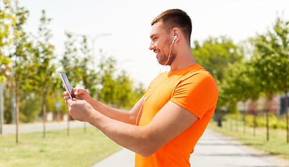 Image showing smiling young man with smartphone and earphones