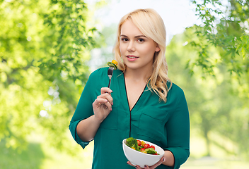 Image showing smiling young woman eating vegetable salad