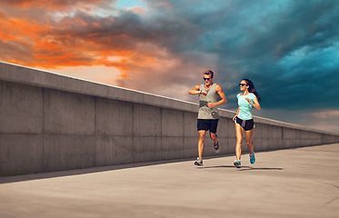 Image showing couple in sports clothes running along pier