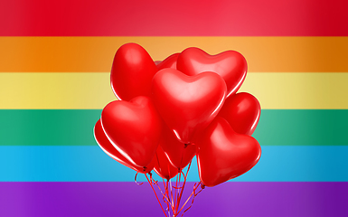 Image showing red heart shaped helium balloons over rainbow flag