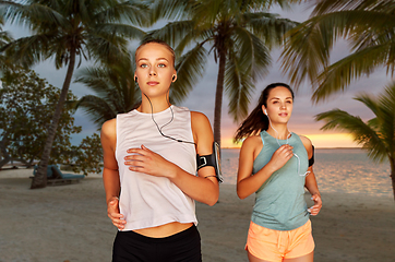 Image showing young women with earphones and smartphones running