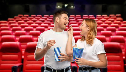 Image showing happy couple in t-shirts eating popcorn at cinema