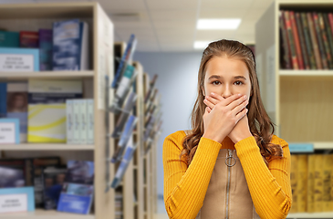 Image showing scared student girl closing mouth at library