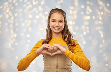 Image showing smiling teenage girl making hand heart