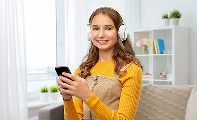 Image showing teenage girl in headphones with smartphone at home