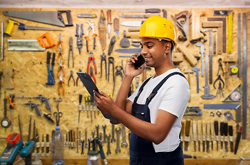 Image showing indian builder with clipboard calling on cellphone