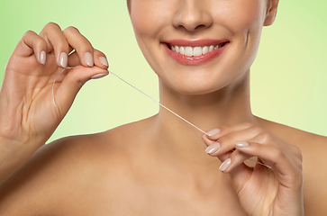 Image showing smiling woman with dental floss cleaning teeth