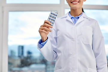 Image showing smiling female doctor with pills at medical office