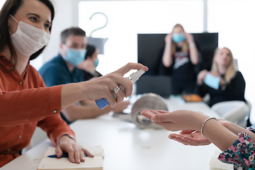 Image showing new normal businesspeople on meeting using antibacterial hand sanitizer