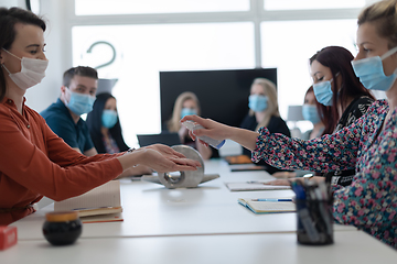 Image showing new normal businesspeople on meeting using antibacterial hand sanitizer