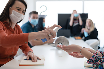 Image showing new normal businesspeople on meeting using antibacterial hand sanitizer