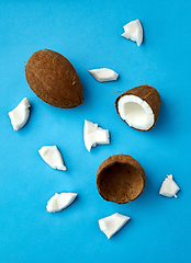 Image showing whole and cracked coconut on blue background