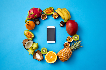 Image showing exotic fruits around smartphone on blue background