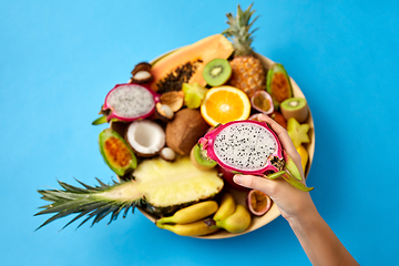 Image showing hand holding half of dragon fruit over blue