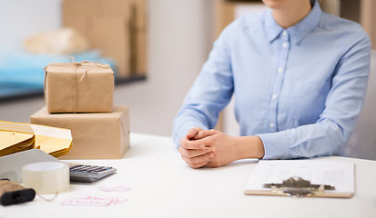 Image showing woman with clipboard and parcels at post office