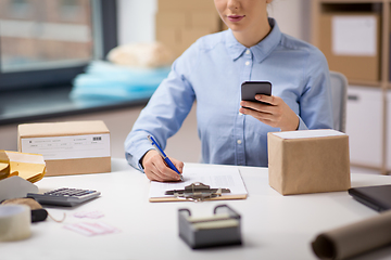 Image showing woman with smartphone and clipboard at post office