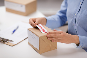 Image showing woman sticking fragile mark to parcel box