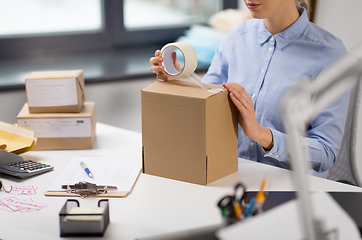 Image showing woman packing parcel box with adhesive tape